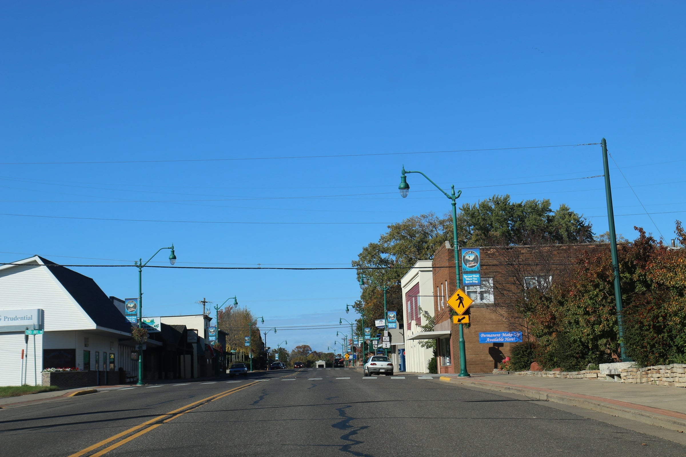 Downtown Balsam Lake along Highway 46 on a clear day, with brick storefronts and street lamps.