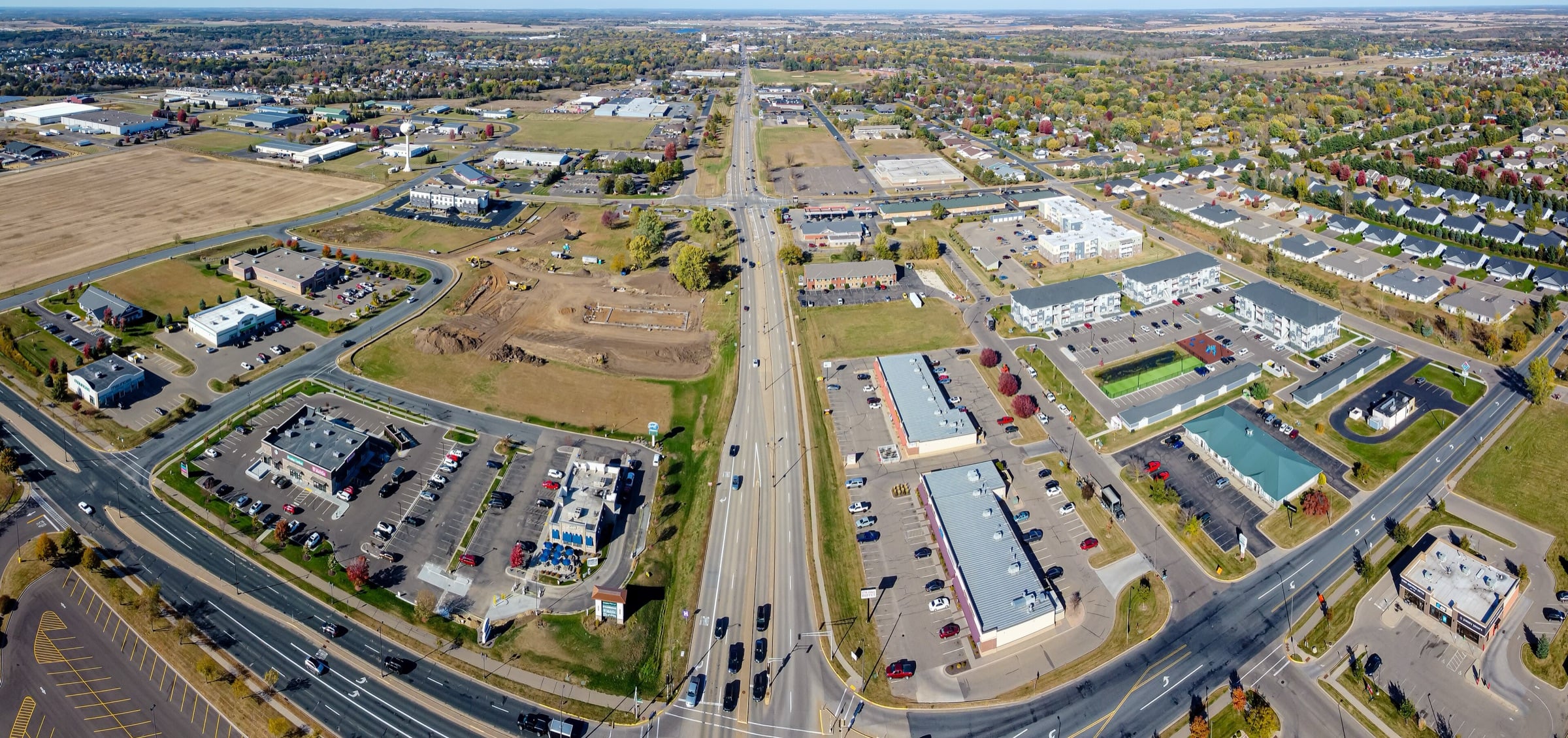 Aerial view of New Richmond, with a highway running through town between commercial buildings, neighborhoods and open fields.