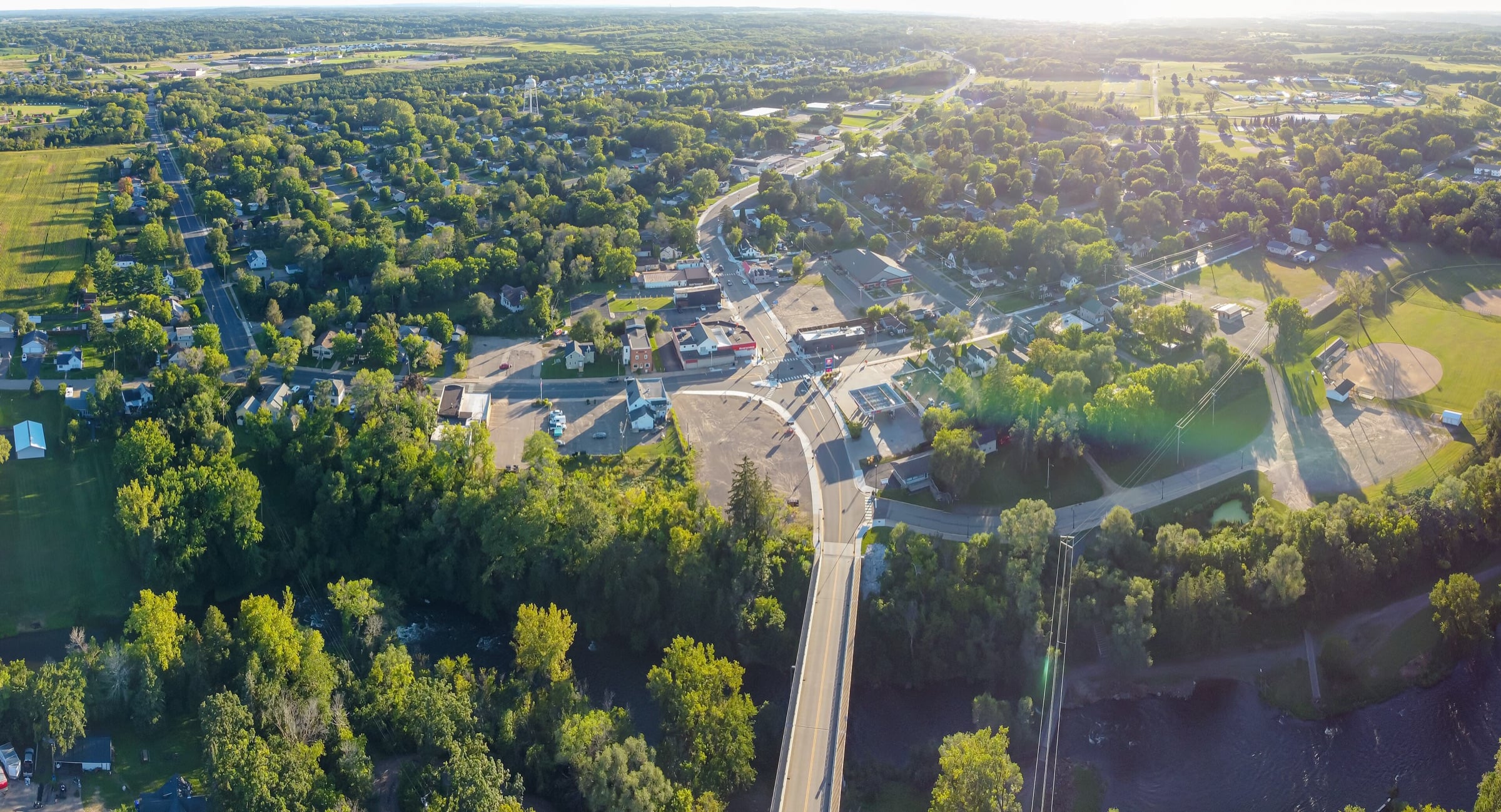 Aerial view of Somerset, with tree-lined neighborhoods and a road curving through the village toward open farmland.
